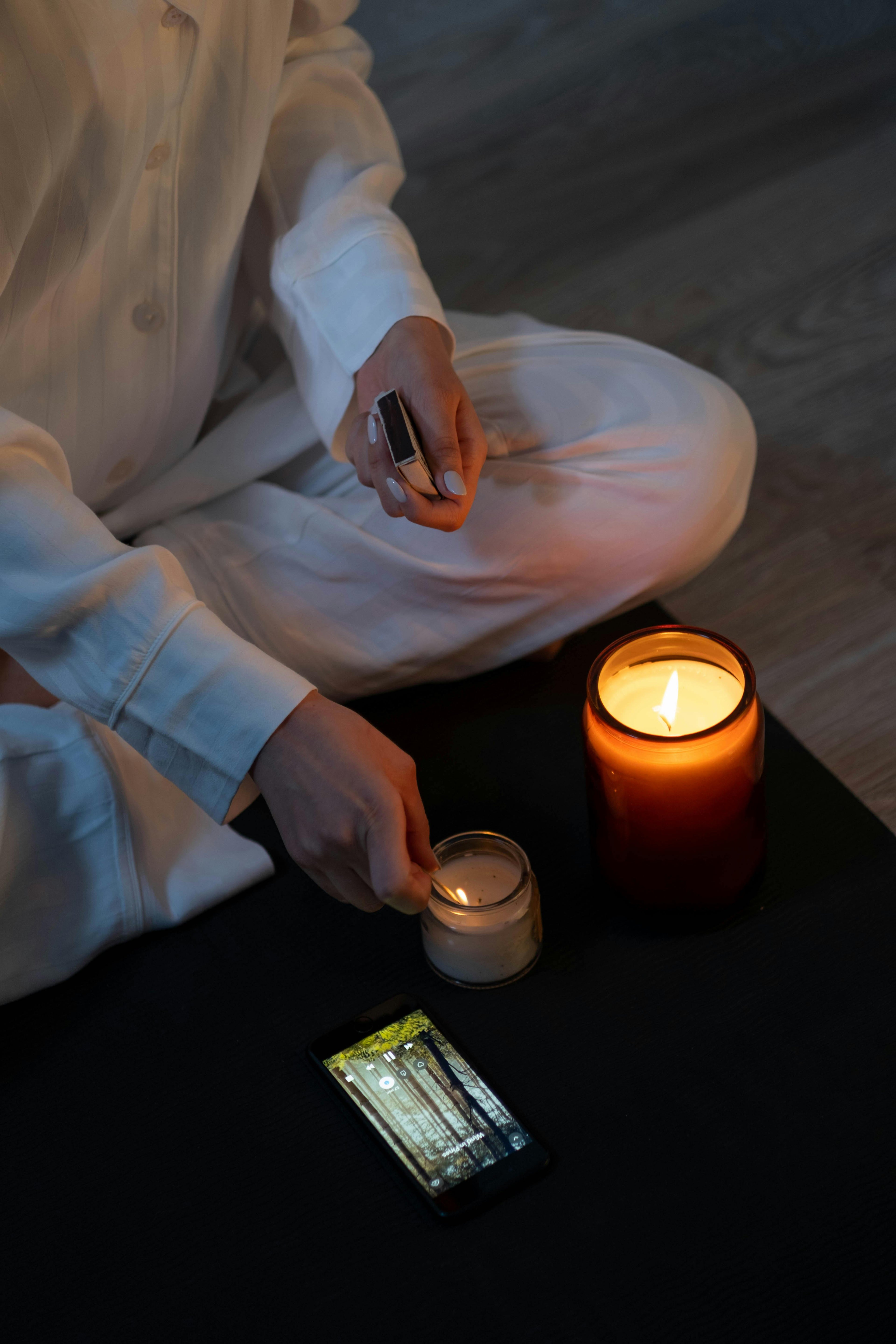 Person lighting a candle during a calm evening routine, illustrating a simple pre-sleep ritual for deeper sleep